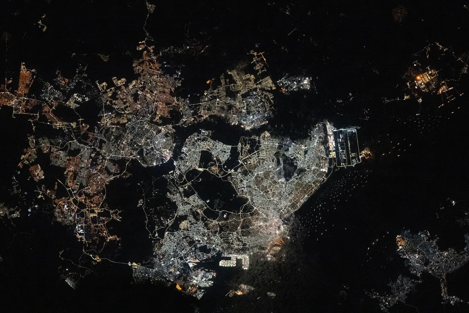 A dense coastal city at night, photographed from orbit